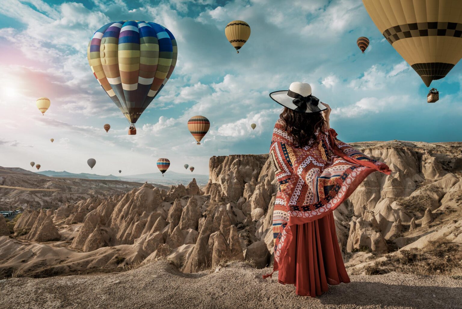 Beautiful girl standing and looking to hot air balloons in Cappadocia, Turkey.